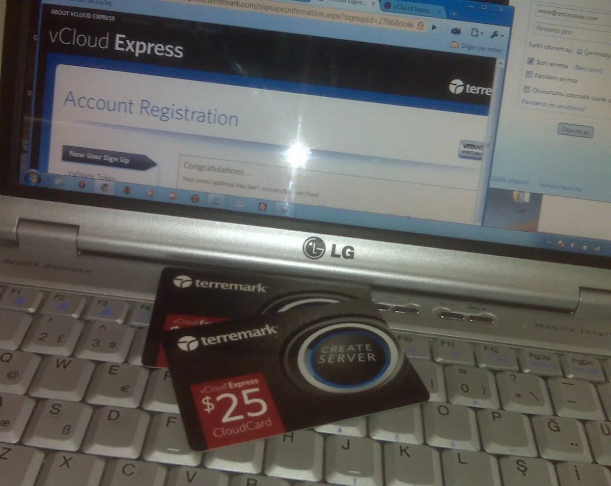 LG W20 laptop showing the Terremark vCloud Express signup page, with a physical $25 CloudCard and a CREATE SERVER invite card on the keyboard, 2010.
